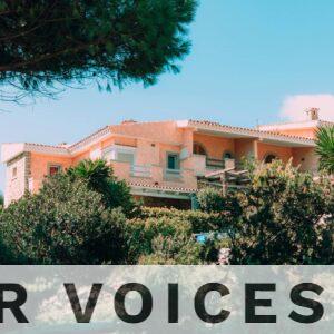 Charming Mediterranean villa nestled in vibrant, lush gardens under a clear blue sky.