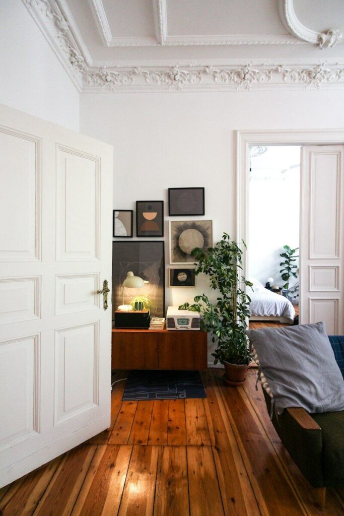 Salón luminoso con arco, muebles de madera y plantas